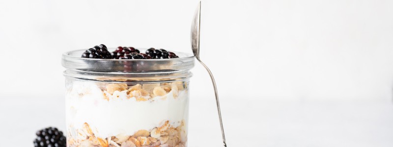 Yogurt parfait with blackberries and granola in a jar. Healthy breakfast, overnight oats or snack. Copy space for text