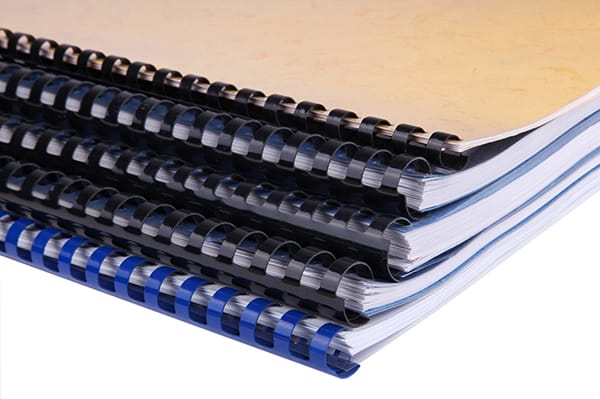Close-up of a stack of spiral notebooks / reports / books over white background
