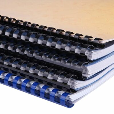 Close-up of a stack of spiral notebooks / reports / books over white background